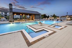 Cumming apartment for rent - A large outdoor swimming pool with a hot tub in the middle.