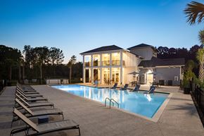 Ridgeville apartment for rent - High-End Apartments in Ridgeville, SC - Preserve at Ridgeville - Resort-Style Pool with Poolside and In-Water Lounge Seats, Umbrella Tables with Chairs, and View of Clubhouse.