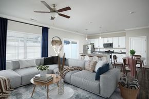 Lenoir City apartment for rent - A modern living room with a grey sofa, a round table, and a ceiling fan.