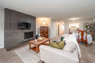 Bellevue apartment for rent - A living room with a grey couch, a wooden coffee table, a fireplace, and a television mounted on a brick wall.