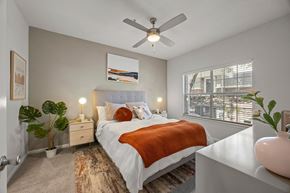 Austin apartment for rent - A bedroom with a bed, a ceiling fan, and a window with blinds.