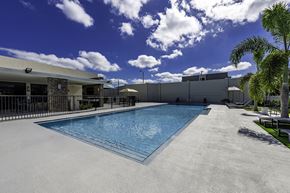 Goulds apartment for rent - A large outdoor swimming pool with a concrete floor and a concrete wall on the right side.