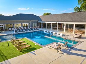 Hixson apartment for rent - A large outdoor swimming pool with lounge chairs and a building in the background.