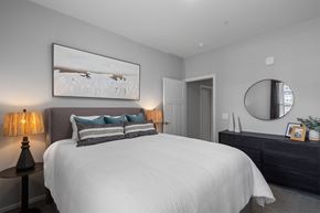 Holland apartment for rent - A bedroom with a large bed, a painting on the wall, and a round mirror above a dresser.
