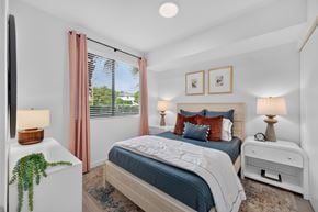 Goulds apartment for rent - A bedroom with a bed, nightstand, and window with curtains.
