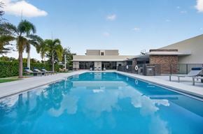 Goulds apartment for rent - A large swimming pool in front of a building with palm trees in the background.
