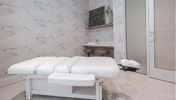 A spa room with four massage tables in front of a wall with a geometric wallpaper