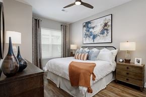 Smyrna apartment for rent - A bedroom with a large bed, a ceiling fan, and a painting on the wall.