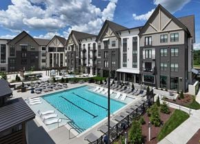 Smyrna apartment for rent - A large swimming pool is surrounded by lounge chairs in front of a large building.