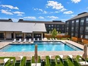 Rogers apartment for rent - A pool surrounded by chairs and umbrellas with a building in the background.