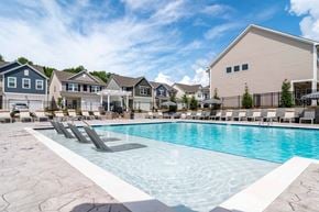 Gainesville apartment for rent - A swimming pool with lounge chairs in front of a row of houses.