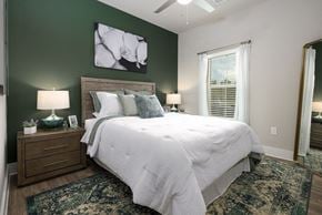 Panama City apartment for rent - Apartments With Boat Parking in Panama City, FL - The Tyde Apartments - Bright Bedroom With Green Accent Wall, Plush Bed, Ceiling Fan, Nightstands, Lamps, and Large Window With Sheer Curtains.