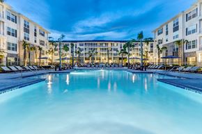 Summerville apartment for rent - A large swimming pool in front of a building with palm trees.