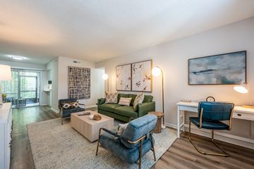 Daytona apartment for rent - A living room with a green couch, a blue chair, and a painting on the wall.
