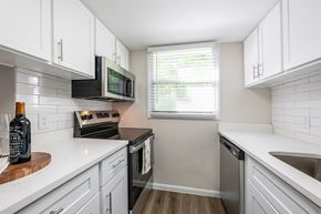 Daytona apartment for rent - A kitchen with white cabinets and a black microwave.