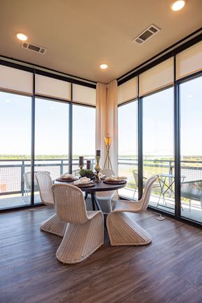 Memphis apartment for rent - Dog-Friendly Apartments in Downtown Memphis, TN - The Landing - Dining Room with Hardwood Flooring, Round Table with Wicker Chairs, and Floor-to-Ceiling Window Walls.