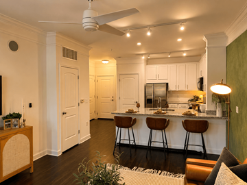 Atlanta apartment for rent - A kitchen with white cabinets and a bar area with brown stools.
