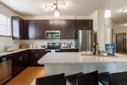 Greenville apartment for rent - One-Bedroom Apartments in Greenville, SC - Velo Verdae - Modern Kitchen with Dark Wood Cabinets, Granite Island Seating, Stainless Steel Appliances, and Pendant Lighting.