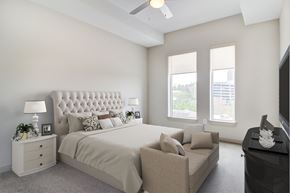 Atlanta apartment for rent - Furnished Apartments in Atlanta, GA - Venue Brookwood - Bedroom with Nightstands, Lamps, Couch, Dresser, TV, Ceiling Fan, and Tall Windows.