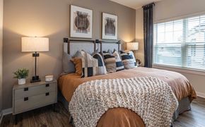 Brunswick apartment for rent - 2-Bedroom Apartments In Brunswick, GA - Vintage Brunswick - Cozy Bedroom With Upholstered Bed, Layered Pillows, Bedside Lamps, Ceiling Fan, And Large Window With Drapes.