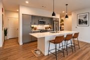 Rogers apartment for rent - A modern kitchen with a white island and brown chairs.