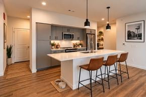 Rogers apartment for rent - A modern kitchen with a white island and brown chairs.