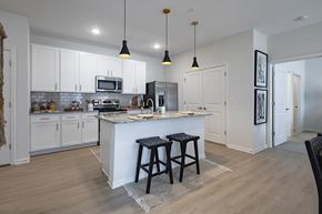 Huntsville apartment for rent - a kitchen with white cabinets and a large island with two stools