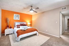 Sandy Springs apartment for rent - A bedroom with orange walls and a white bed.