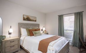 Charlotte apartment for rent - A bedroom with a large bed, a nightstand with a lamp, and a painting on the wall.
