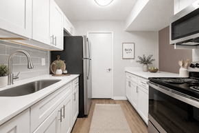 Norcross apartment for rent - A kitchen with white cabinets and a black refrigerator.