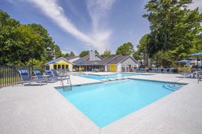Norcross apartment for rent - A large swimming pool surrounded by trees and a building in the background.