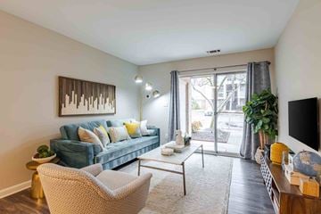 Lorton apartment for rent - A living room with a blue couch, a chair, a coffee table, and a painting on the wall.