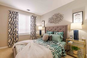 Lorton apartment for rent - A bedroom with a large bed and a decorative wall hanging.