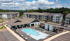 Huntsville apartment for rent - A large building complex with a pool in the foreground.