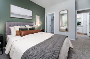 Alexandria apartment for rent - Alexandria, KY, Apartments with In-Unit Washer and Dryer - Elevation Apartment Homes - Bedroom with 9-Foot Ceiling, Carpet Flooring, Large Bed with Pillows, Nightstands, Lamp, Wall Arts, Wall Mirror, and a View of the Oversized Closet and Bathroom.
