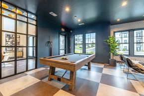 Greenville apartment for rent - A pool table is in the middle of a room with a black ceiling and a checkered floor.