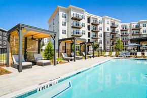Sugar Hill apartment for rent - A swimming pool in front of apartment buildings with lounge chairs and a pergola.