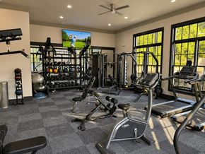 Atlanta apartment for rent - A spacious gym with a variety of equipment including treadmills, weights, and a television.