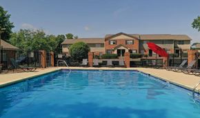 Athens townhouse for rent - A swimming pool in front of a brick building with a red umbrella.
