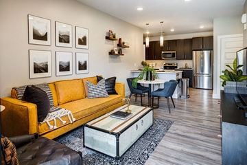 Bozeman apartment for rent - a living room with a yellow couch and a table and a kitchen
