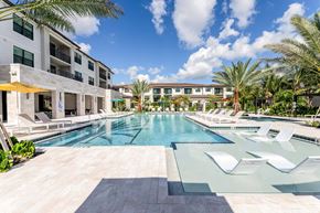 Wellington apartment for rent - A large swimming pool with sun loungers in front of apartment buildings.