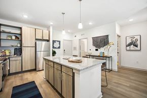 Flagler Beach apartment for rent - 3-Bedroom Luxury Apartments in Flagler Beach, FL - Preserve at Flagler Beach - Modern Kitchen With Granite Island, Light Wood Cabinetry, Stainless Steel Refrigerator, And Pendant Lighting.