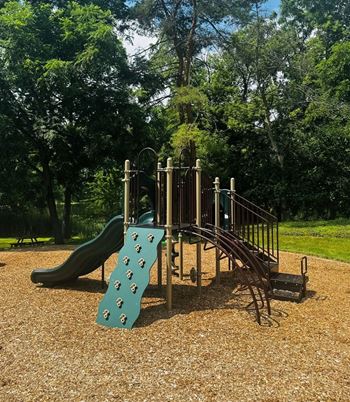 A playground with a green slide and a brown structure