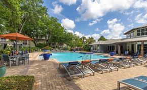 Pensacola apartment for rent - A pool area with sun loungers and a building in the background.