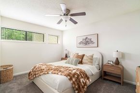 Knoxville townhouse for rent - A bedroom with a bed covered in a brown blanket and a ceiling fan above it.