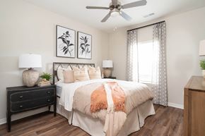 Alcoa apartment for rent - Dog-Friendly Luxury Apartments in Alcoa, TN - Vintage Hunters Crossing - Bedroom with a Bed, Hardwood-Inspired Flooring, Nightstands, Lamps, Wall Arts, Dresser, and Ceiling Fan with Lighting.