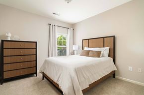 Lenoir City apartment for rent - A bedroom with a large bed and a wooden dresser.