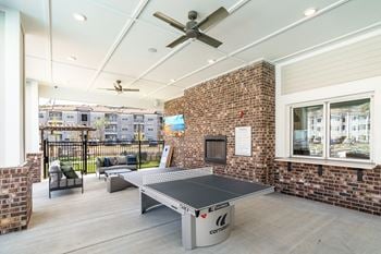 Outdoor beer garden styled with decorative lighting, private seating, fire pit, corn hole, and covered grilling stations