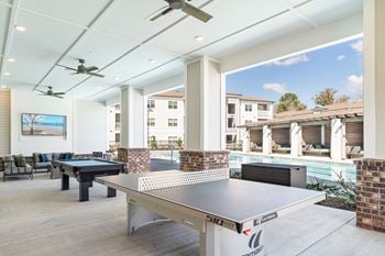 Outdoor beer garden styled with decorative lighting, private seating, fire pit, corn hole, and covered grilling stations