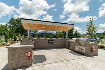 Two outdoor gathering spaces with gas grills, firepits, seating areas and large screen televisions